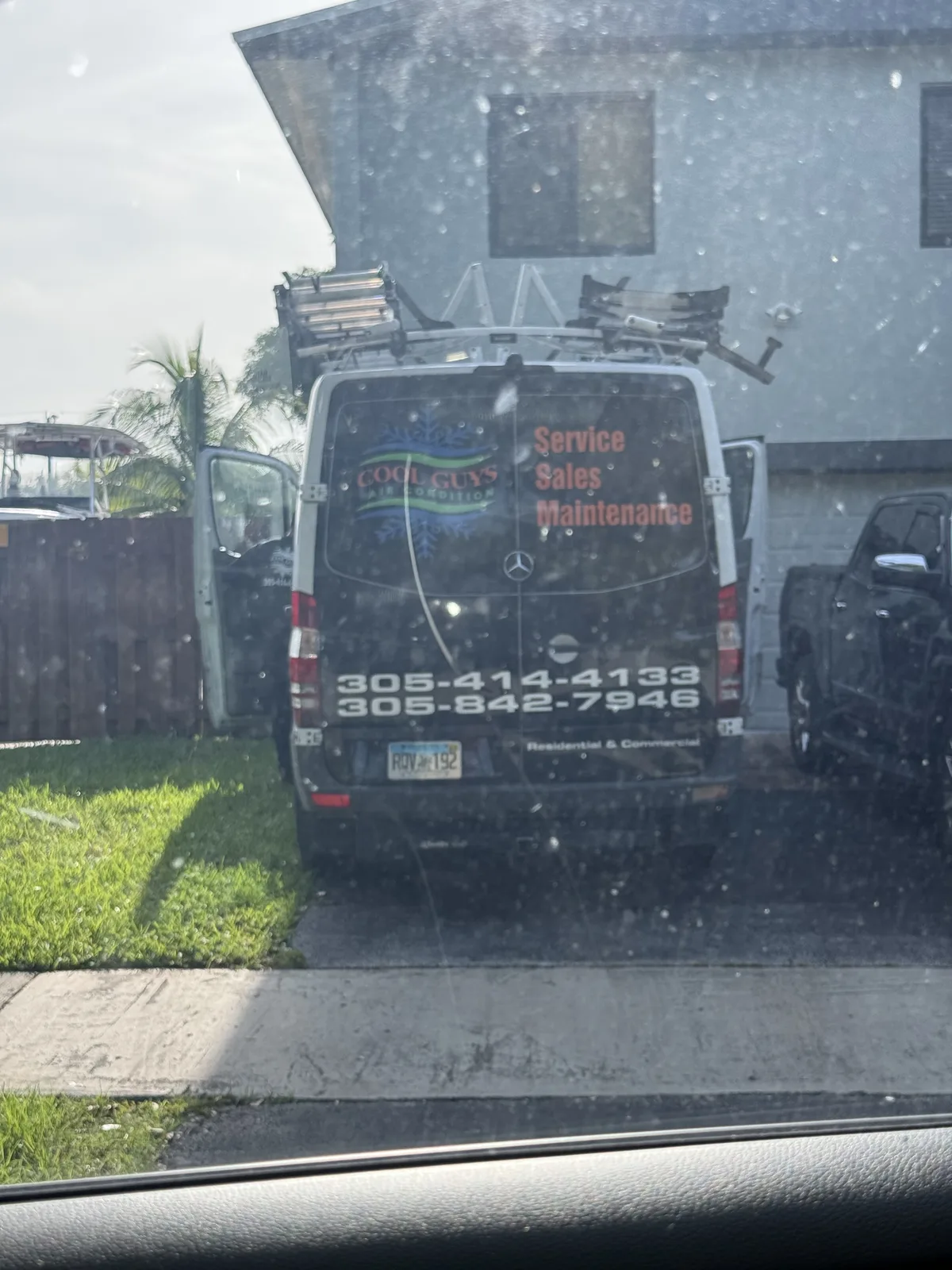 Black Cool Guys Air Conditioning service van with two phone numbers on the rear doors