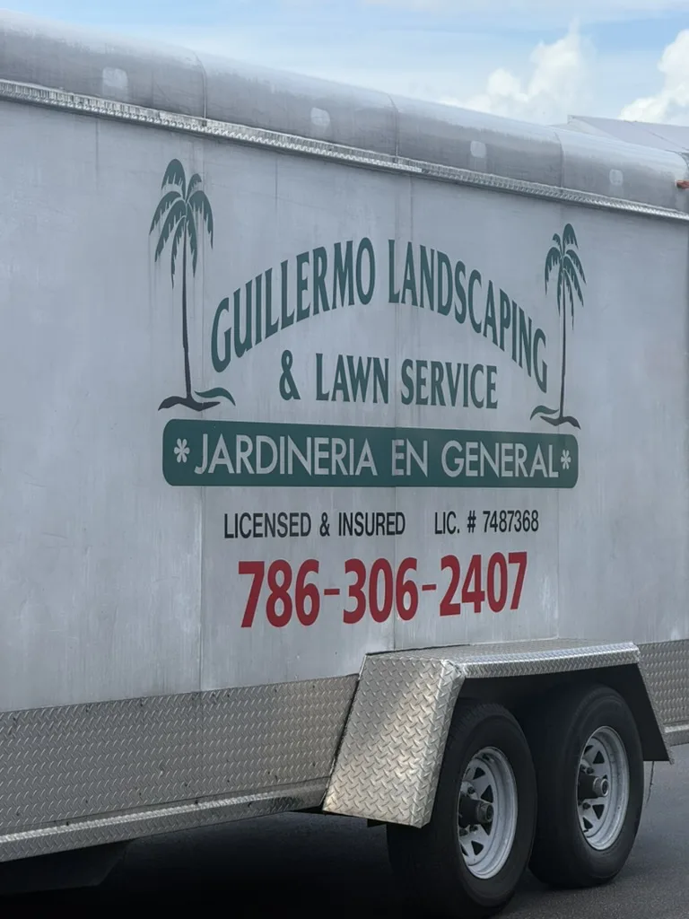 White Guillermo Landscaping and Lawn Service trailer with bilingual gardening text and phone number