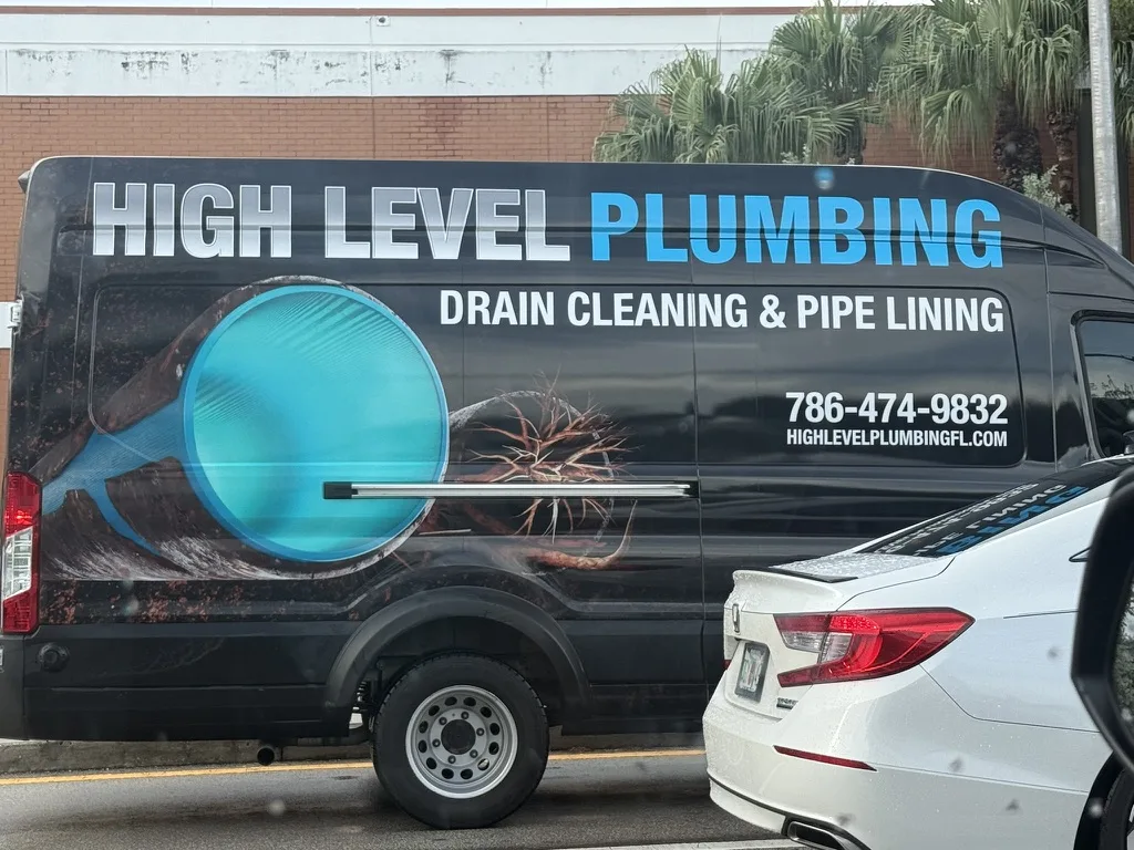 Black High Level Plumbing van advertising drain cleaning, pipe lining, phone number, and website