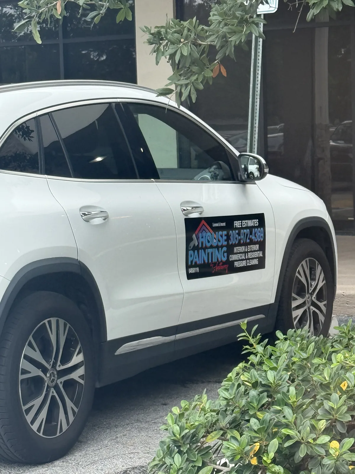 White SUV displaying a House Painting sign with phone number 305-972-4369 and painting services