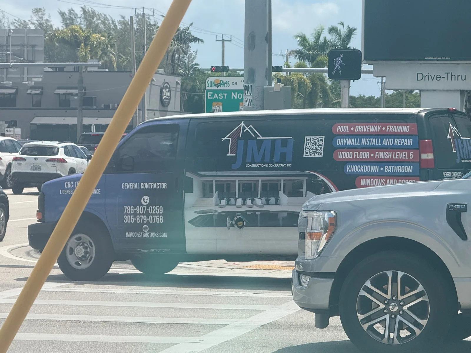 White JMH Construction and Consultant work van displaying two phone numbers, a website, and construction services