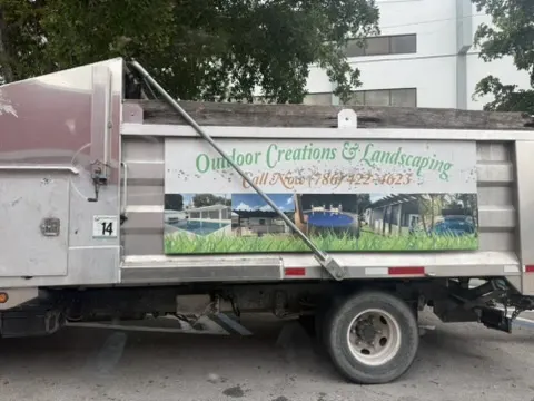 Outdoor Creations and Landscaping work truck with project photos and phone number 786-422-9023