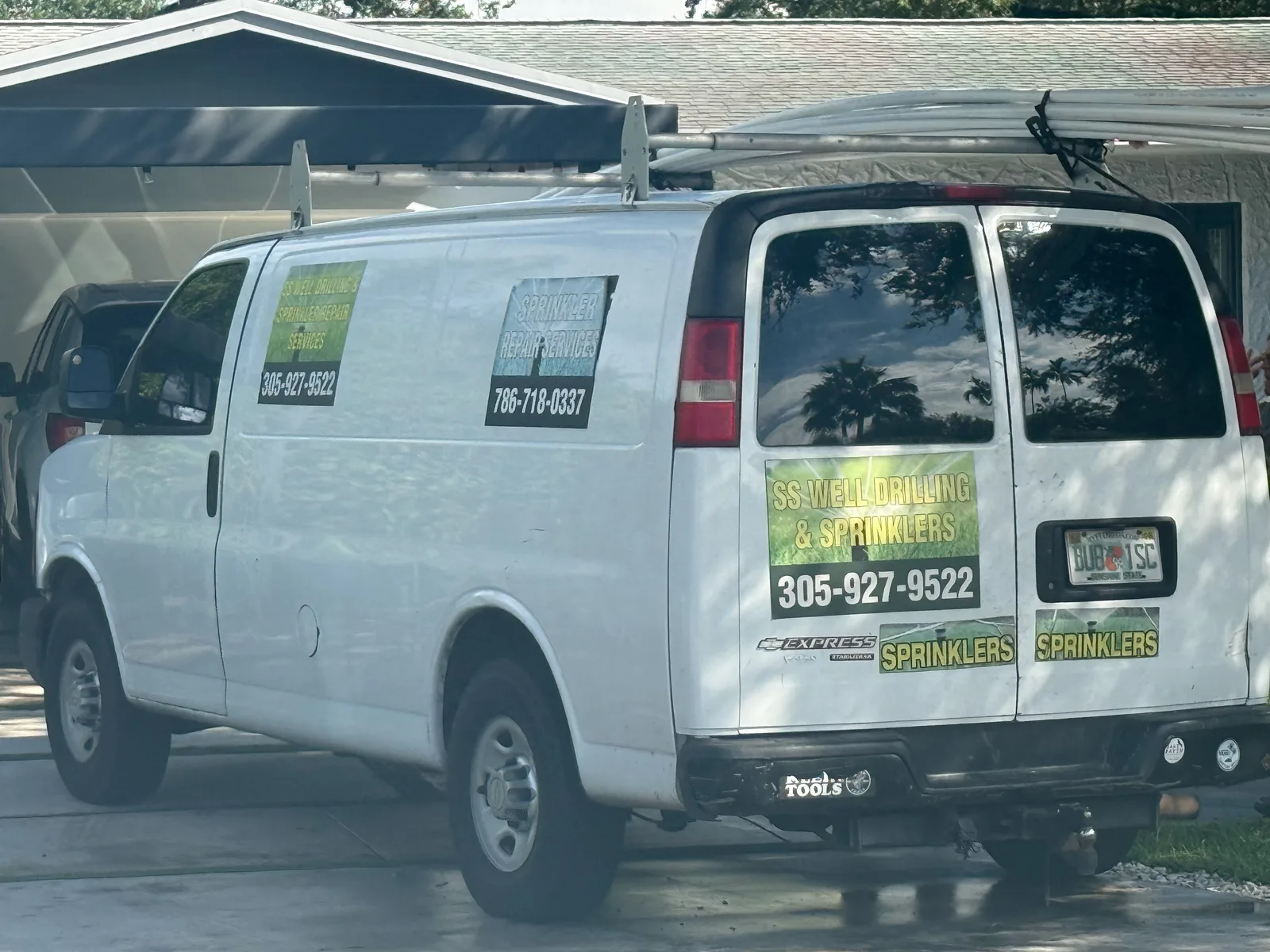 White SS Well Drilling & Sprinklers work van displaying 305-927-9522 and a sprinkler-repair sign with 786-718-0337