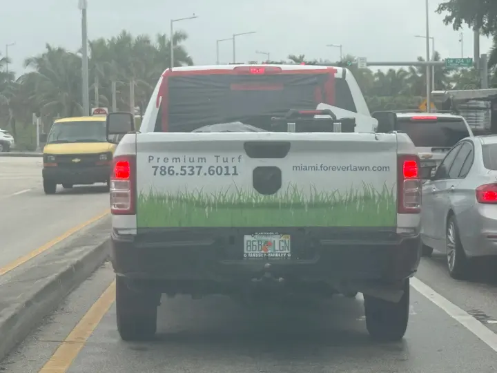 White ForeverLawn Miami pickup truck marked Premium Turf with phone number and website on the tailgate