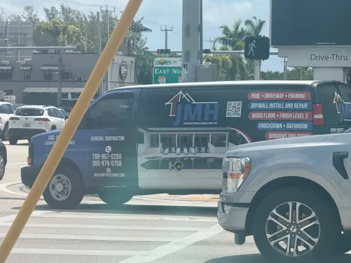 White JMH Construction and Consultant work van displaying two phone numbers, a website, and construction services