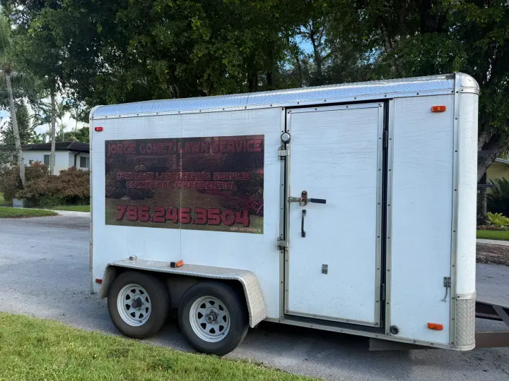 Jorge Gomez Lawn Service equipment trailer displaying landscaping services and phone number 786-246-3504