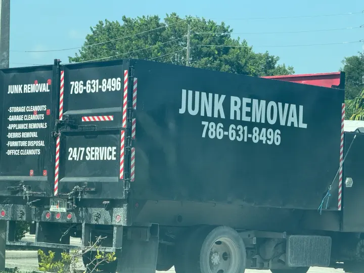 Black junk-removal truck displaying cleanout services and phone number 786-631-8496