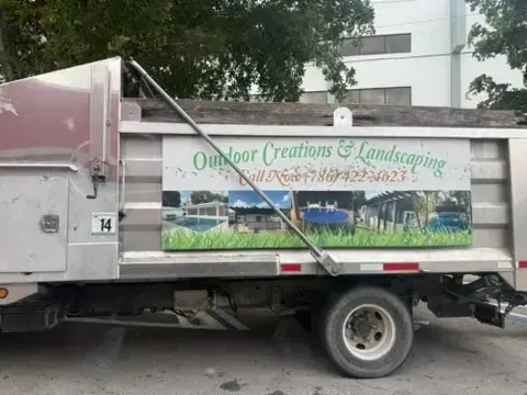 Outdoor Creations and Landscaping work truck with project photos and phone number 786-422-9023