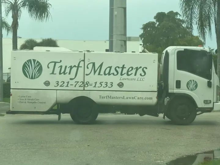 Turf Masters Lawn Care work vehicle displaying its business name and contact information