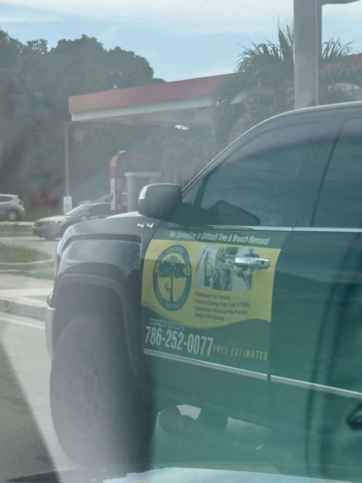 Dark pickup truck advertising tree trimming and tree and branch removal with phone number 786-252-0077