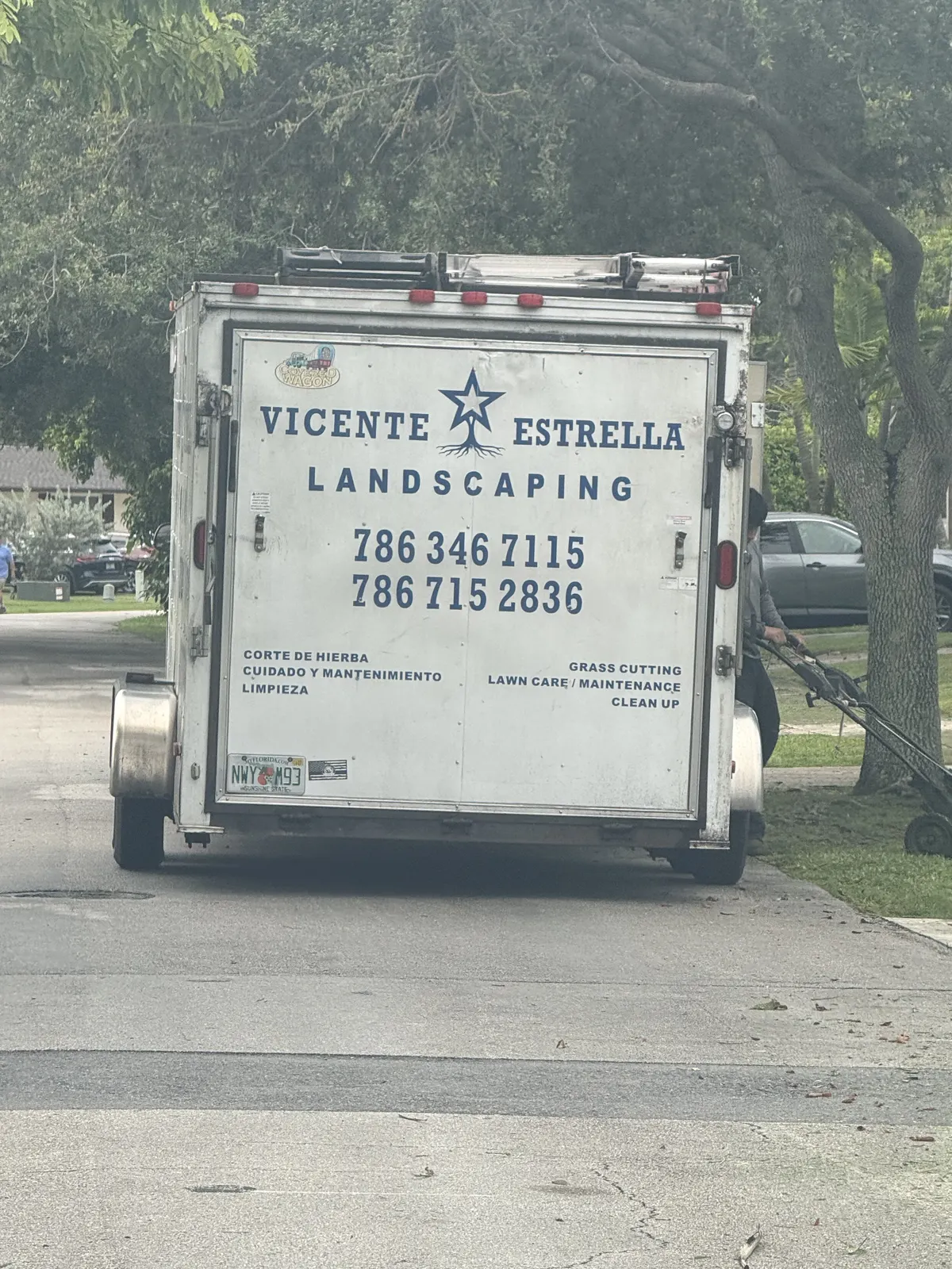 White Vicente Estrella Landscaping trailer with bilingual lawn-care services and two phone numbers