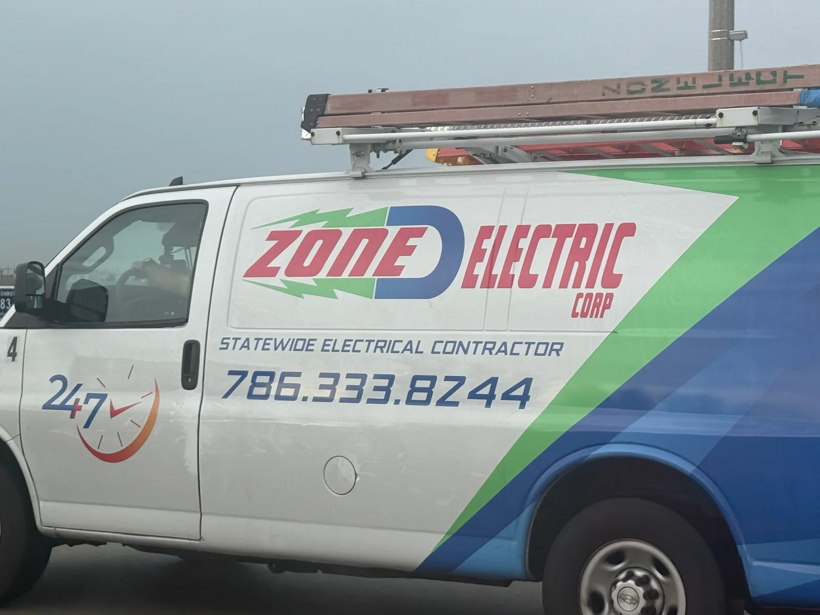 Zone D Electric Corp work vehicle displaying its business signage and contact information